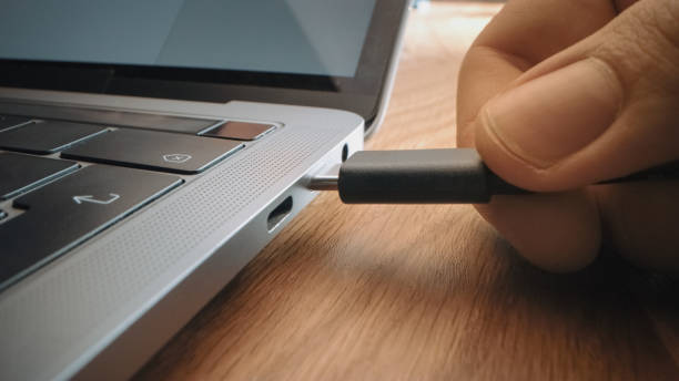 istock Close-up Macro Shot: Laptop on the Desk, Person Inserts USB-C Cable Adapter into Computer Port. 1219143144
