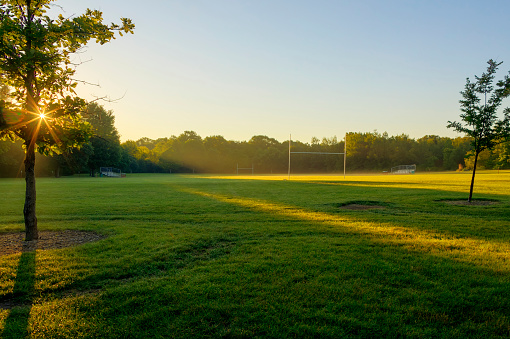 as dawn breaks over a football field in a city park