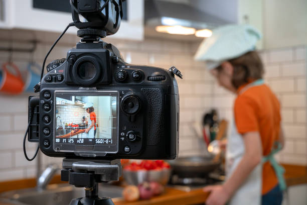 istock Child making recording on a tripod mounted camera in kitchen. 1219144488