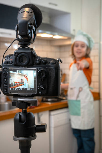 istock Child making recording on a tripod mounted camera in kitchen. 1219144595