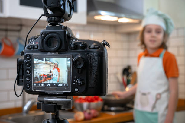istock Child making recording on a tripod mounted camera in kitchen. 1219144688