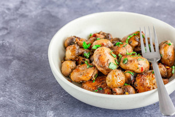 champiñones salteados con mantequilla de ajo directamente por encima de la foto de primer plano - saute fotografías e imágenes de stock