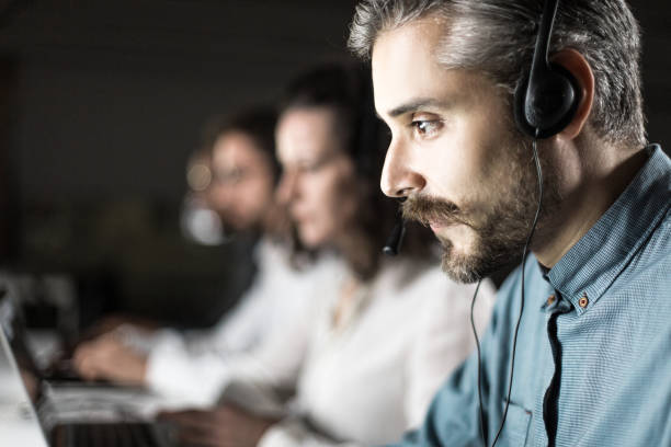 istock Side view of handsome young man with headset looking at laptop 1219154595