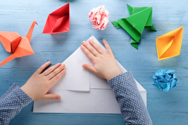 istock The child makes origami from colored paper. 1219154706
