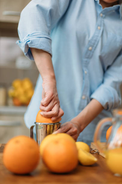 istock Young woman making juice from fresh oranges at home 1219154746