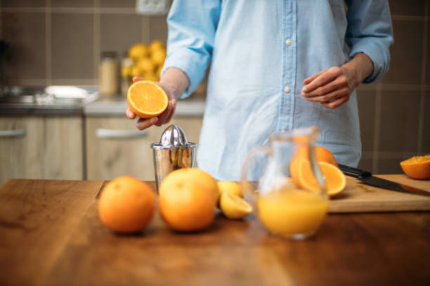 istock Young woman making juice from fresh oranges at home 1219154761