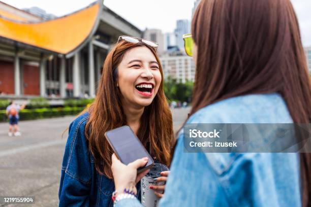 Two Female Friends Talking On The City Street Stock Photo - Download Image Now - Device Screen, Laughing, Telephone