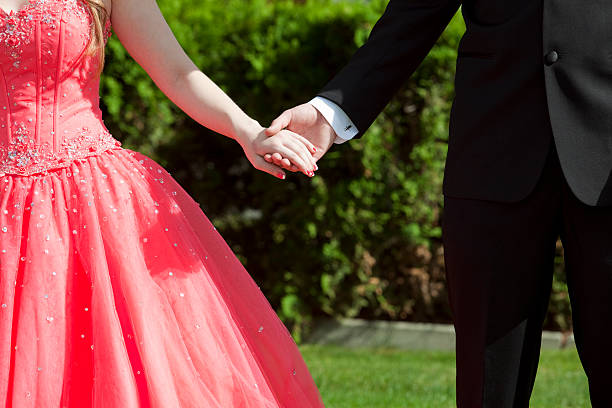 Girl dressed in red for prom holding hands with date