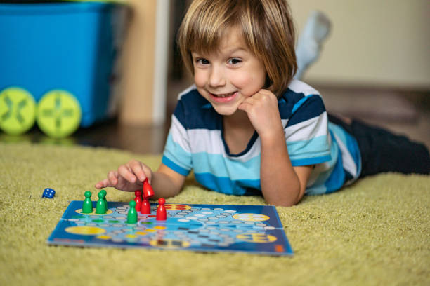 istock Cute boy holds the player from the board game and plays the next move 1219158985