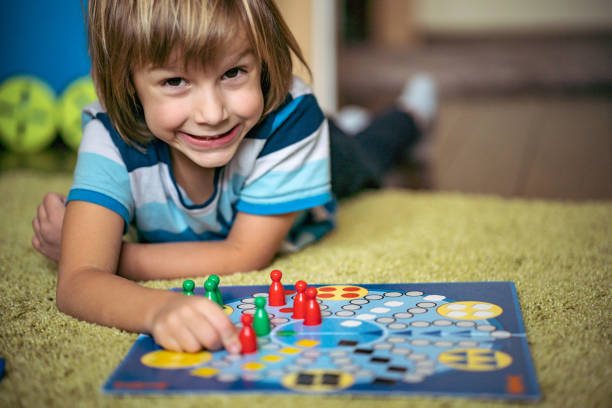 istock Cute boy lays on the floor and playing board game 1219159218