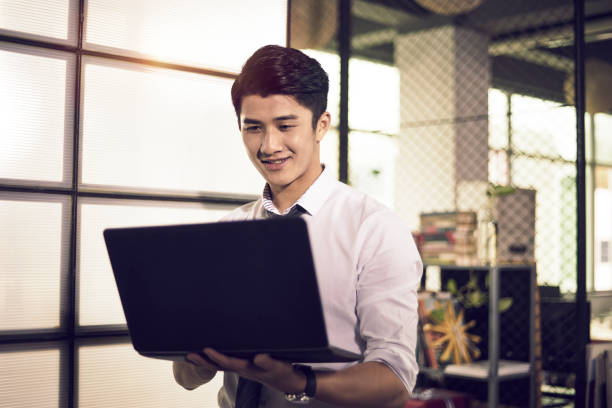 istock young asian business man looking at laptop smiling 1219159393