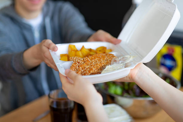 прохождение пластикового контейнера выемок пищи по столу - deep fried people fried chicken стоковые фото и изображения