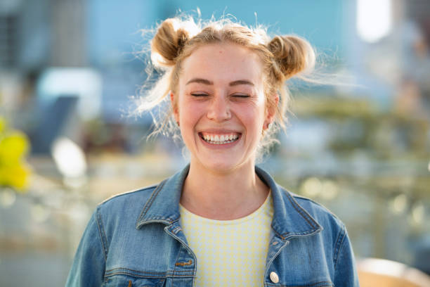 Loving Life A portrait of a young Caucasian woman standing on a hotel rooftop in Perth, Australia. She is smiling with her eyes closed. hair bun stock pictures, royalty-free photos & images
