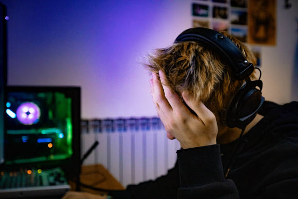 young boy facepalming después de perder en el videojuego - foto de archivo - men mental illness loss despair fotografías e imágenes de stock