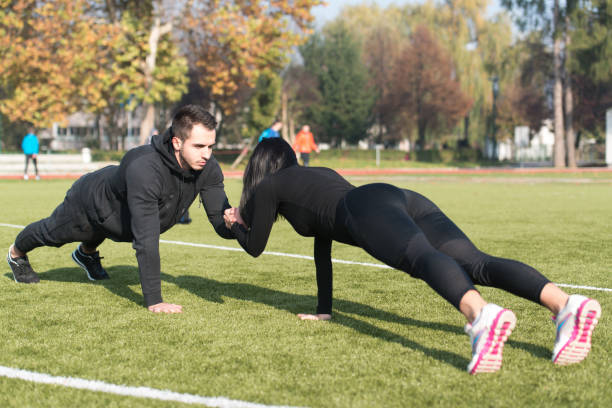 istock Sports Couple Doing Pushups in the Park 1219165015