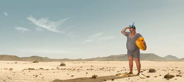 Divertido nadador con sobrepeso en busca de la playa en medio del desierto photo