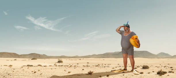 Funny overweight swimmer searching for the beach  in the middle of the desert Funny overweight swimmer looking for the beach  in the middle of the desert with copy space lost stock pictures, royalty-free photos & images