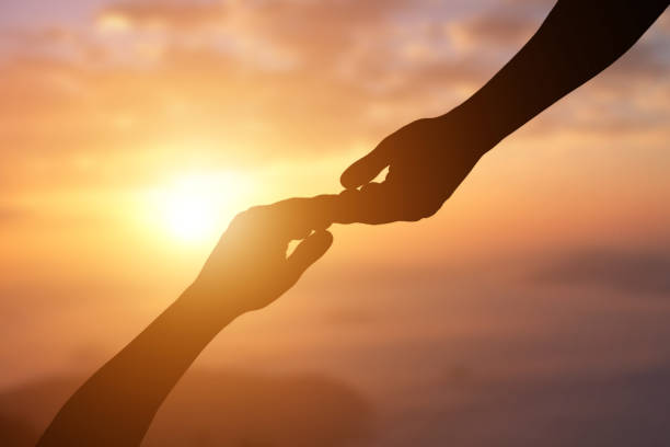 istock Silhouette of giving a helping hand, hope and support each other over sunset background. 1219165975
