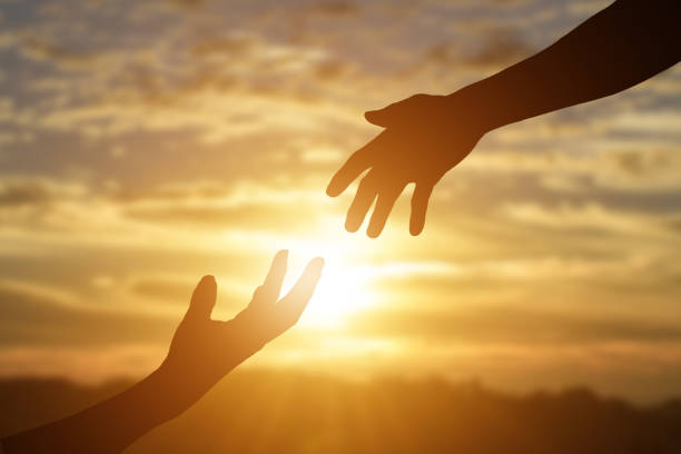 istock Silhouette of giving a helping hand, hope and support each other over sunset background. 1219166106