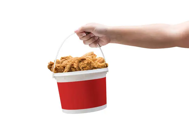 Photo of A hand holding a bucket of crispy fried chicken on a white background