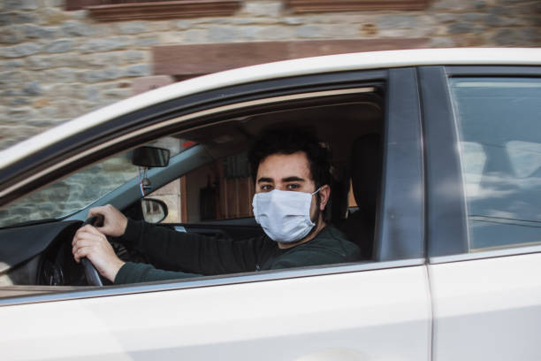 istock Man driving a car with face mask 1219168878