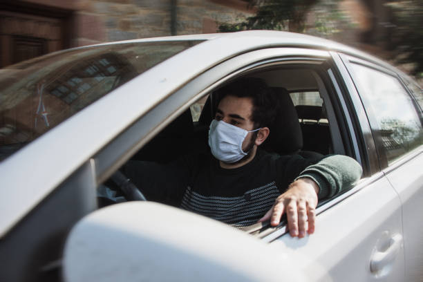 istock Man driving a car with face mask 1219169194