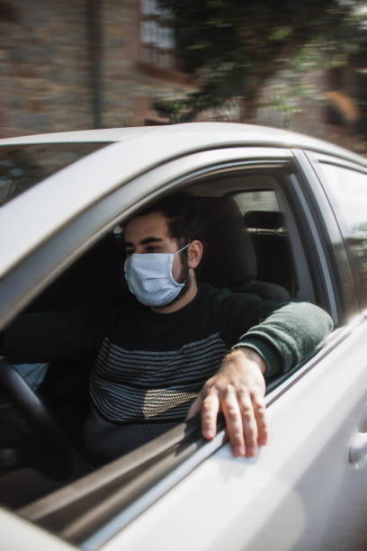istock Man driving a car with face mask 1219169233