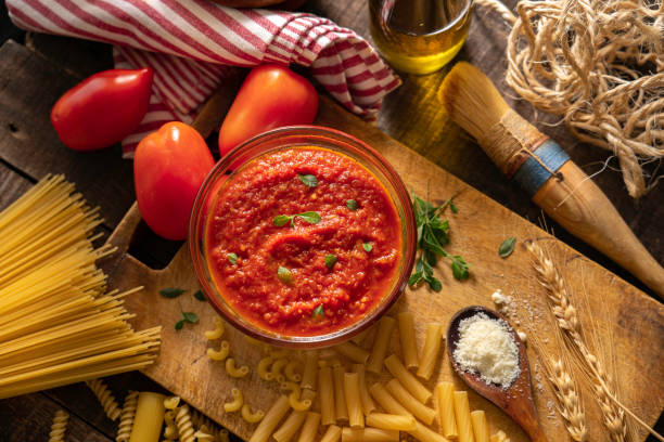 Tomato sauce and raw pasta composition Italian tomato sauce surrounded by different kinds of uncooked pasta and ingredients (tomatoes, olive oil and parmesan cheese). tomato rigatoni stock pictures, royalty-free photos & images