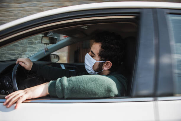 istock Man driving a car with face mask 1219170419