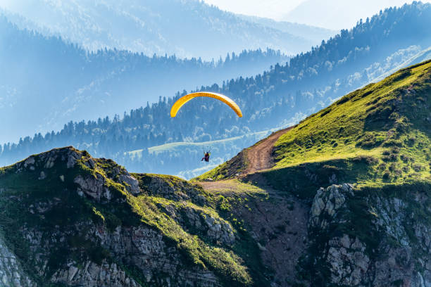 istock Yellow paraglider fly over mountain slope on sunny summer day, 1219170445