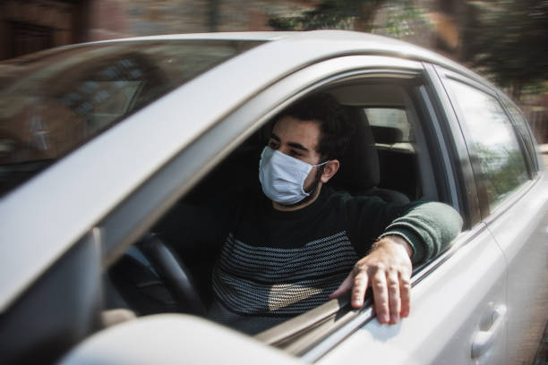 istock Man driving a car with face mask 1219170671