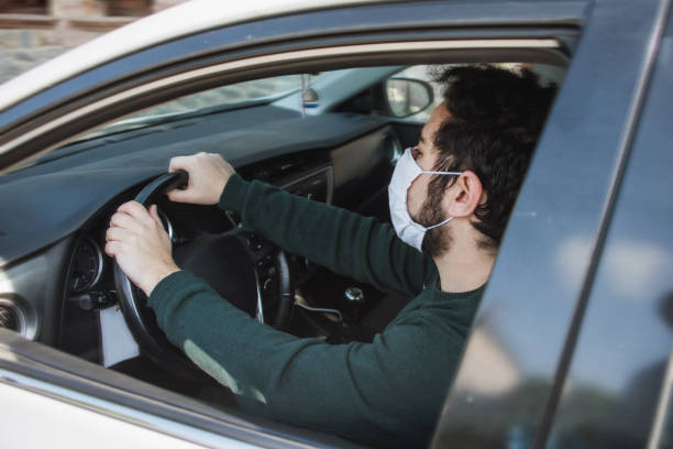 istock Man driving a car with face mask 1219170850