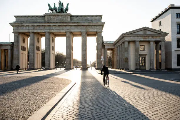 Lone biker riding past Berlin's Brandenburg Gate as the city experiences its first day with movement restrictions introducing by the German government to mitigate the spread of COVID-19 Corona-virus