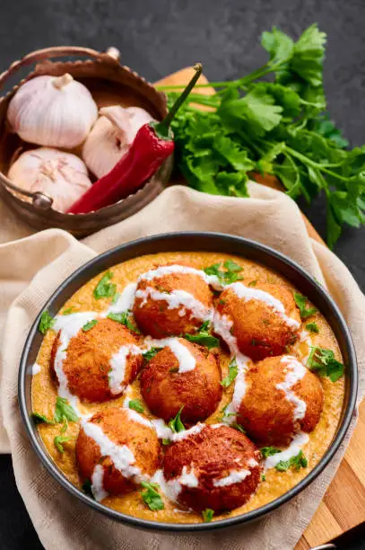 Malai Kofta Curry in black bowl. Malai Kofta is indian cuisine dish with potato and paneer cheese deep fried balls in onion tomato gravy with spices. Indian Food.