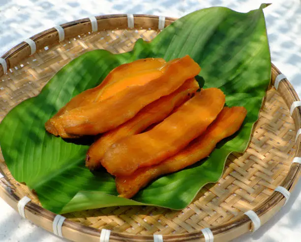Bamboo tray of homemade food for snack diet, sliced yellow sweet potato that dried by sun exposure in hot day at Vietnam