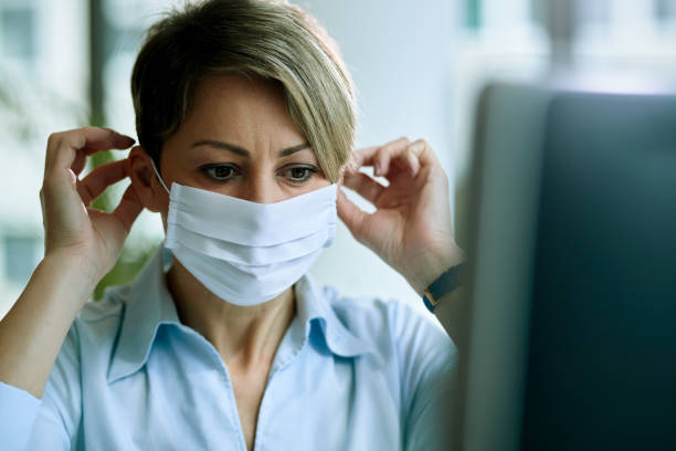 istock Businesswoman putting on face mask while preparing for work in the office. 1219180091