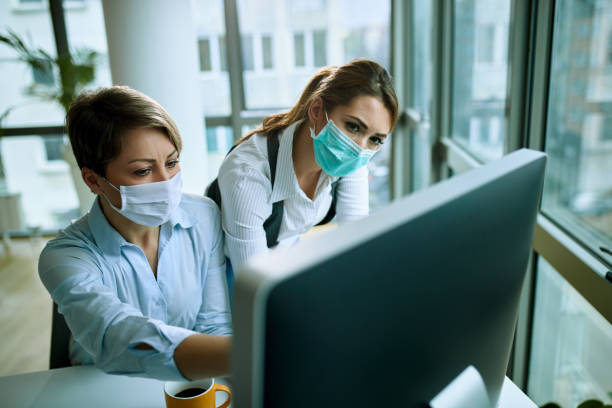 istock Two businesswomen with face masks working on a computer in the office. 1219180435