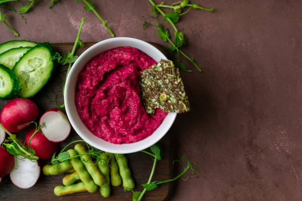 istock Beetroot hummus, fresh greens, vegetables, ckackers served on a wooden board. Top view with copy space 1219180839
