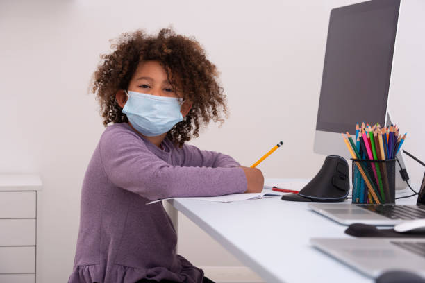 istock Child with face mask studying online. Studying remotely. Distance Learning. Coronavirus pandemic concept. 1219182786