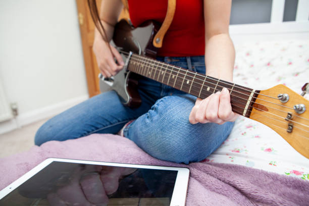 istock Teenager learning guitar with lesson on digital tablet 1219182917