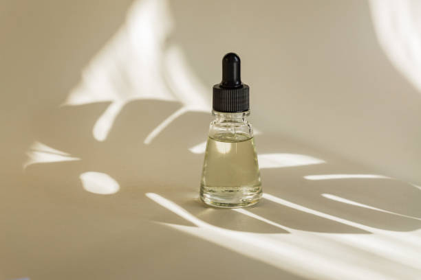 istock Essential oils with drops pipette on beige background. Monstera shadows. Professional bottle for facial and body treatment. 1219184228