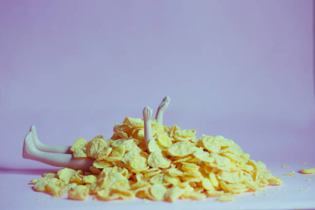 istock A doll covered with cornflakes on a pink background, gluttony, greed, diet, isolation concept 1219184288