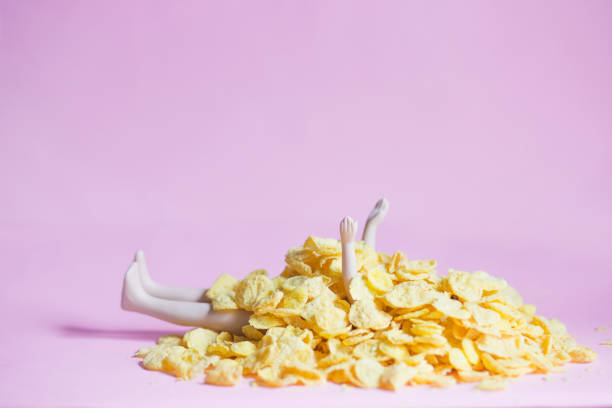 istock A doll covered with cornflakes on a pink background, gluttony, greed, diet, isolation concept 1219184314