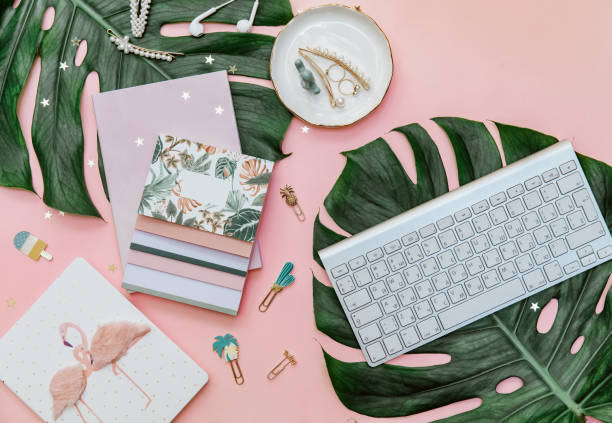 istock Pink tropical office desk table with notebook, computer keyboard and other office supplies. Creative blogger concept 1219186566