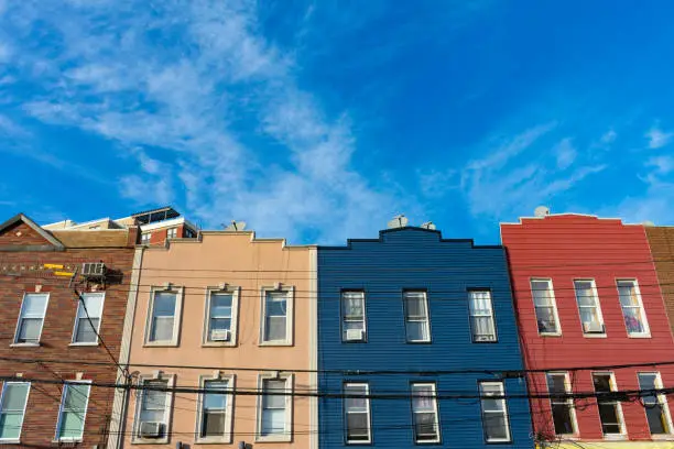 Looking up at a row of colorful brick and wood buildings and a background of a blue sky in Astoria Queens New York