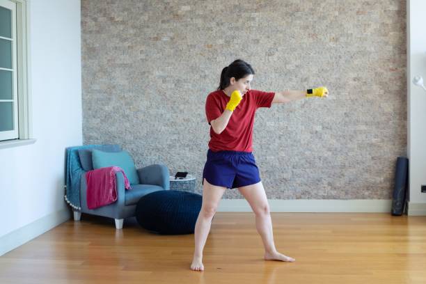 donna millenaria che pratica arti marziali a casa - yellow box foto e immagini stock