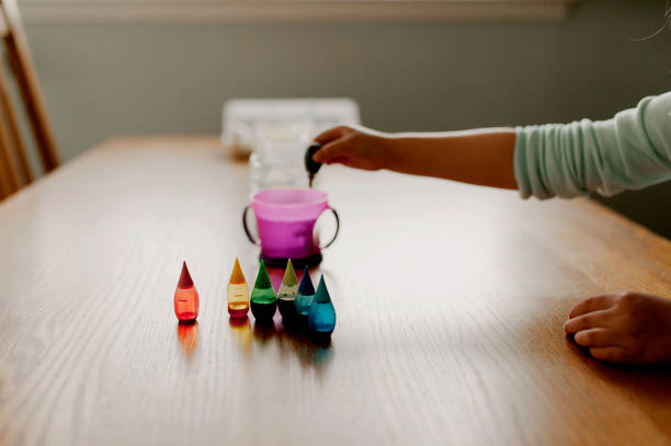 Bambino che aggiunge gocce di colorante alimentare alla tazza - foto stock