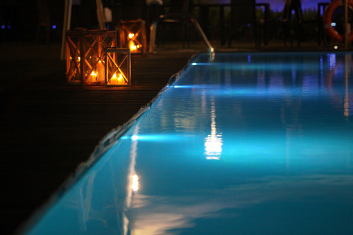 Luxury villa with swimming pool and patio furnitures at night.