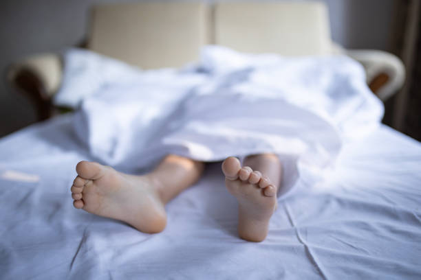 Two little feet are sticking out of a bedsheet