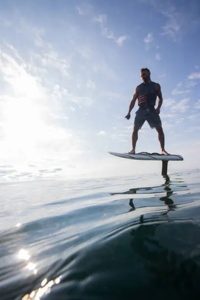 Man riding an electric hydrofoil board on a lake with a life jacket